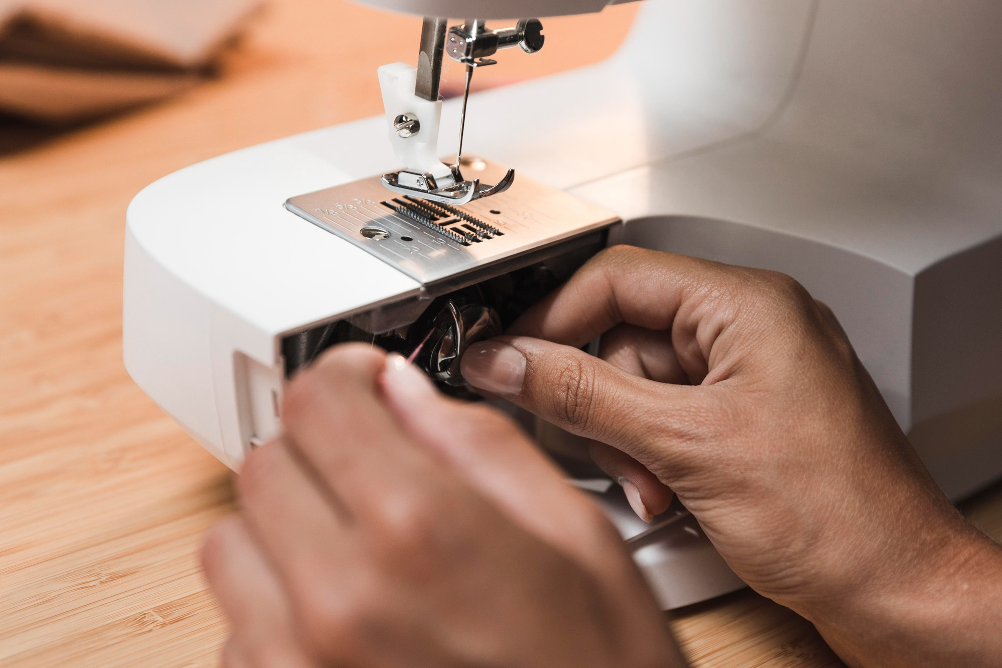 Mains réglant le crochet et la canette d'une machine à coudre blanche